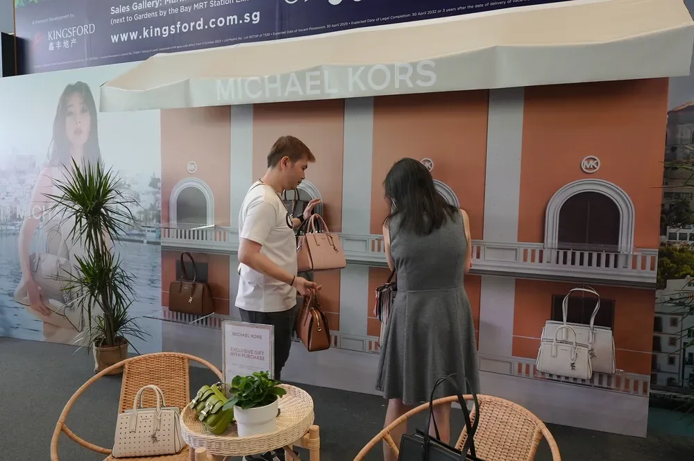 Guests examining handbags at a Michael Kors event display