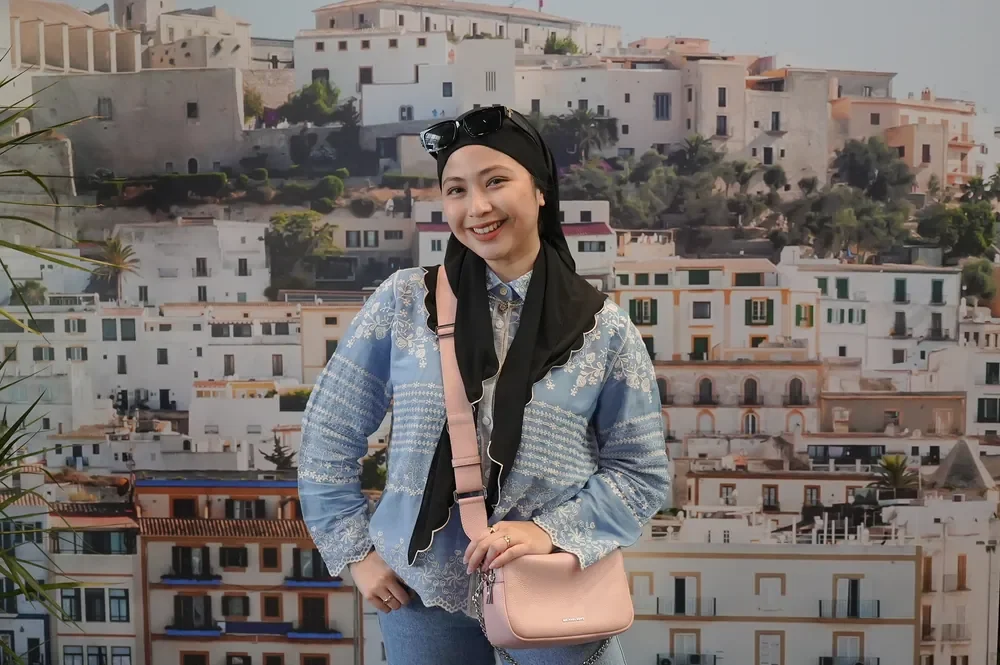 Guest holding a pink Michael Kors handbag against the campaign backdrop