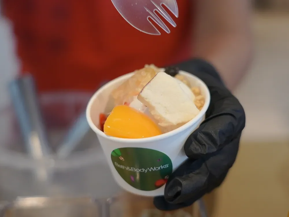 Gloved server adding toppings to a Bath & Body Works dessert cup