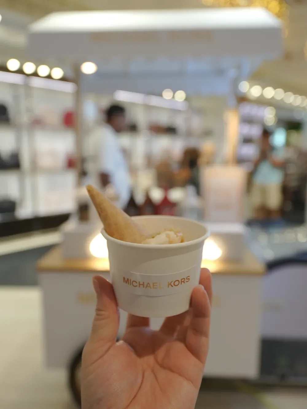 Hand holding a Michael Kors gelato cup in front of the cart